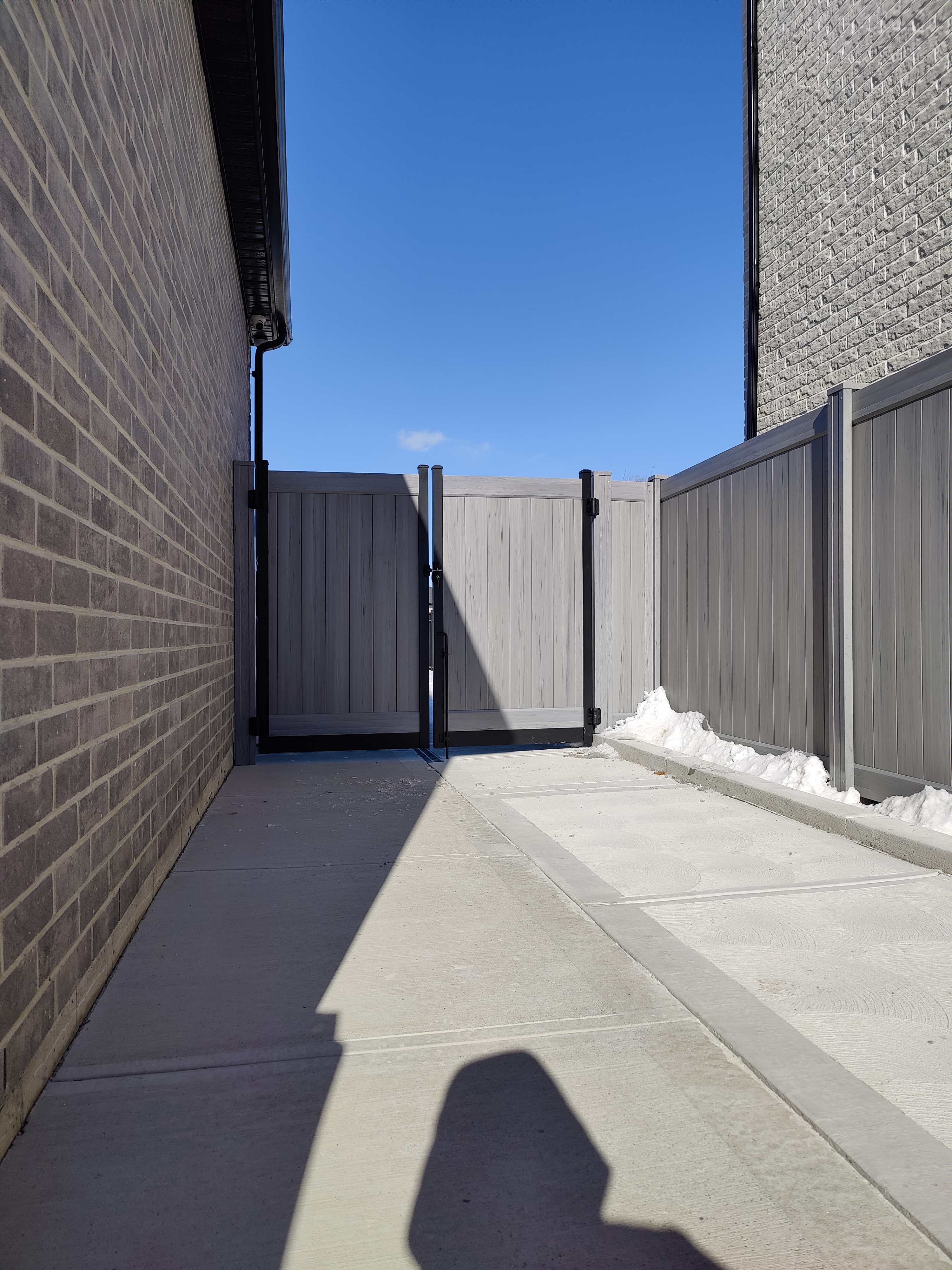 Vinyl gate with a welded aluminum frame powdercoated in matte black with Homeland chai grey infill