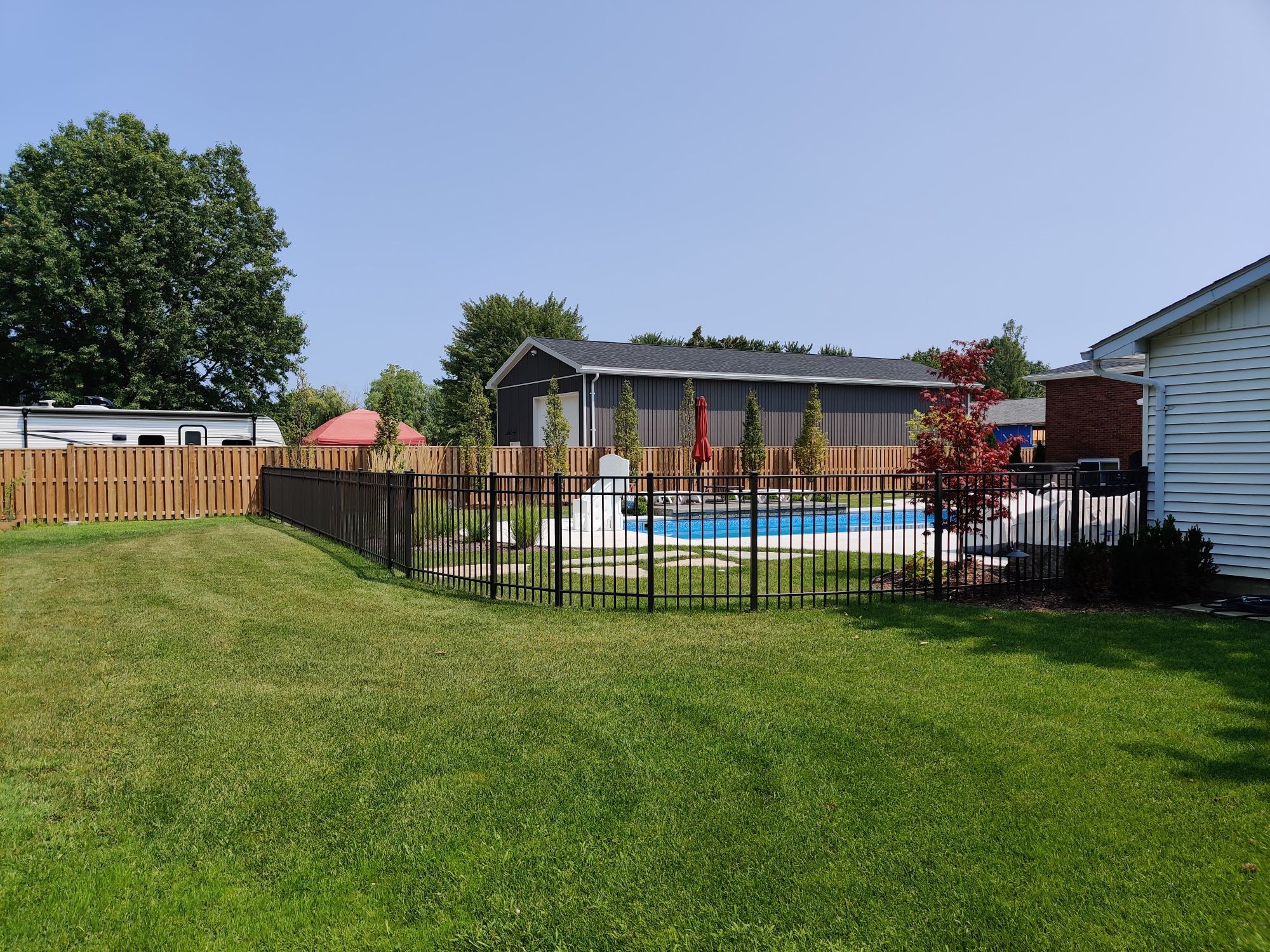 Curved fence in Puce at this beautifully landscaped yard with a pool. EFF-20 Matte Bronze Residential Fence